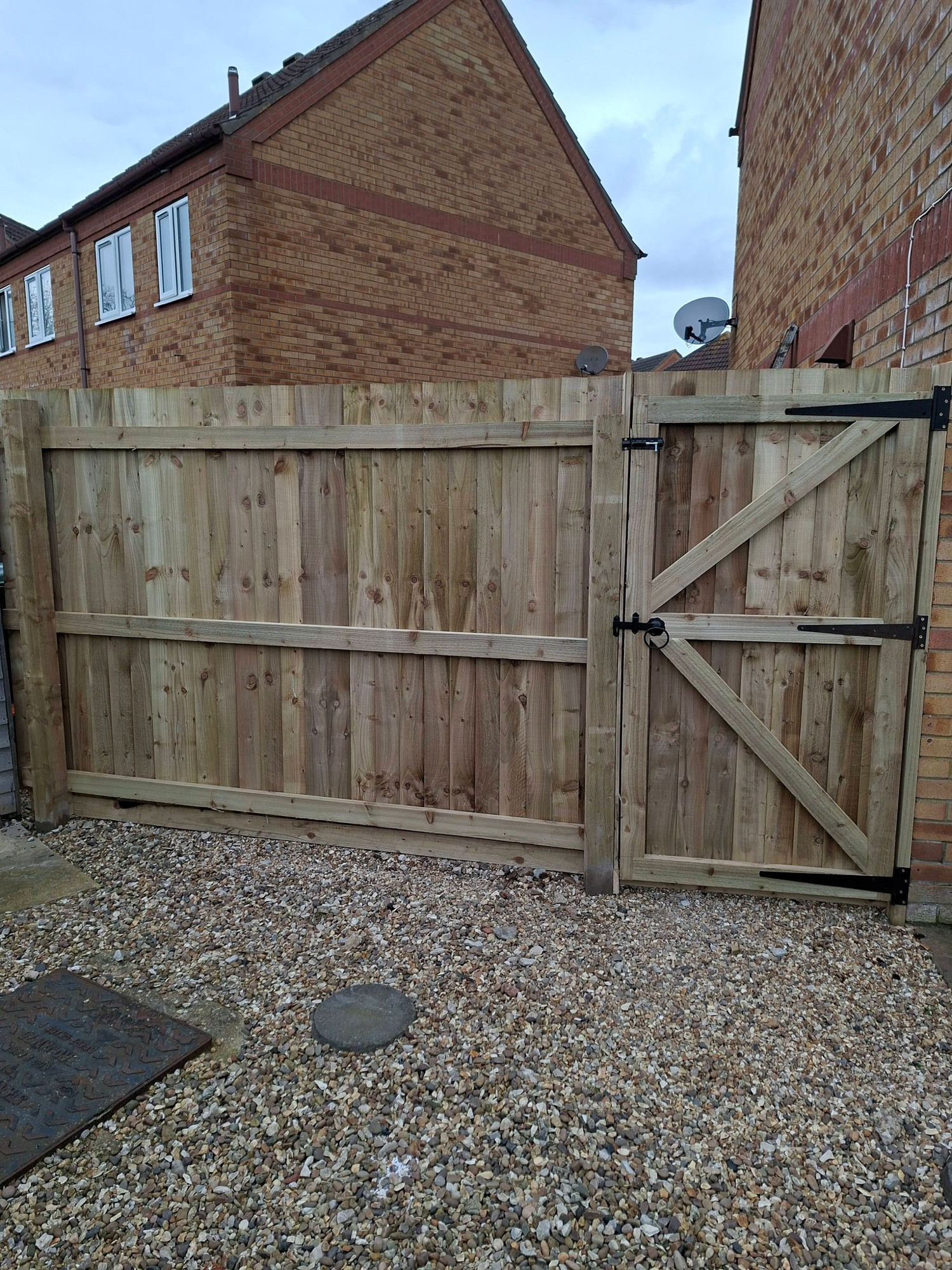 New feather-edge timber fence with matching framed gate and gravel base